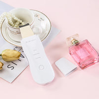 Vibrating facial cleansing spatula held in hand for scale